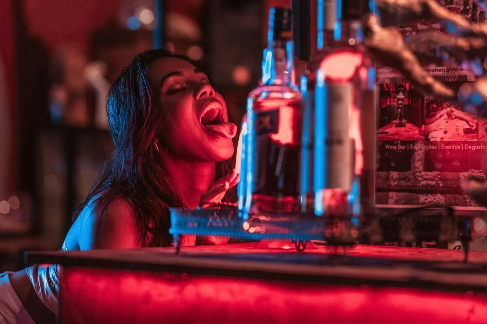 Woman enjoying nightlife in a vibrant bar setting with glowing lights and drinks in Rio de Janeiro.